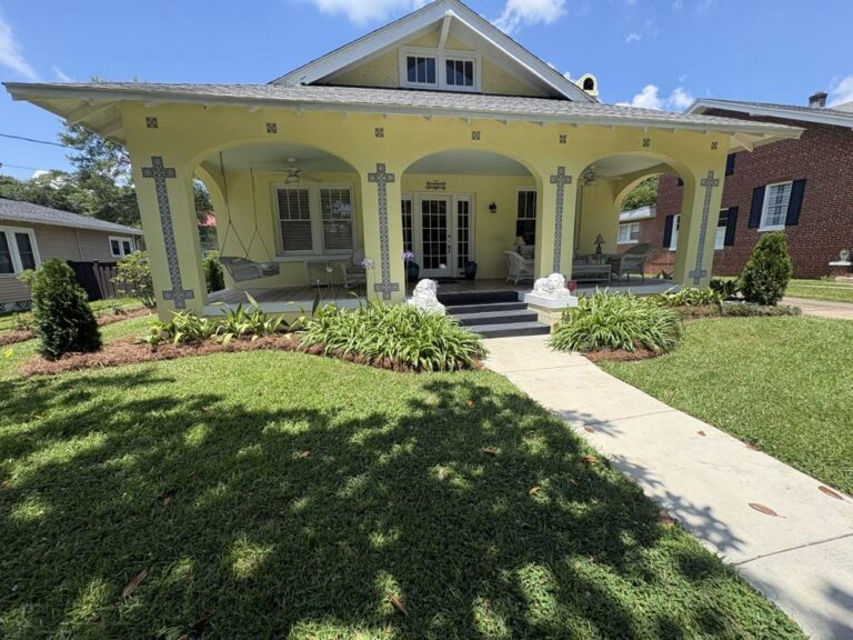 Freshly mowed front lawn and walkway at a yellow craftsman house