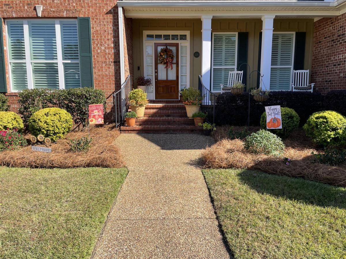 Fresh pine straw beds along the front porch of a brick home