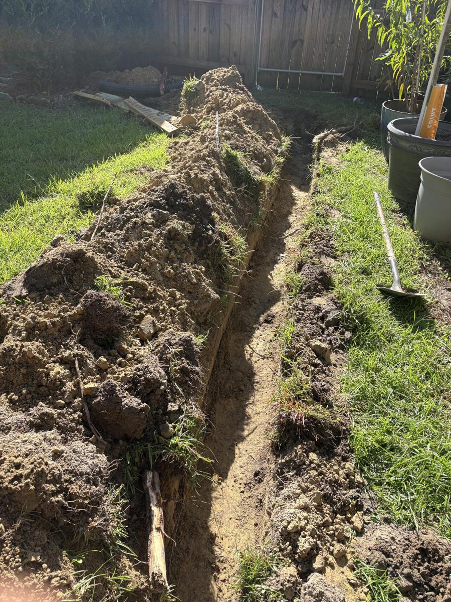 Open drain trench running along a backyard fence